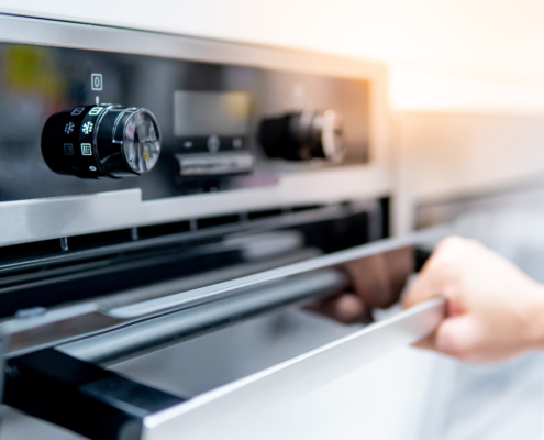 Male hand opening oven door in the kitchen showroom. Buying cooking appliance for domestic kitchen. Home improvement concept